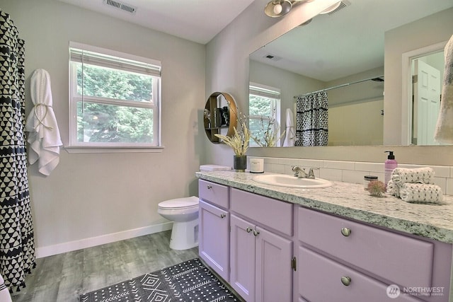 bathroom featuring toilet, wood finished floors, visible vents, and baseboards