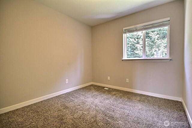 spare room featuring carpet floors, visible vents, and baseboards