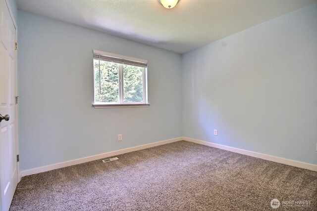 carpeted empty room featuring baseboards and visible vents