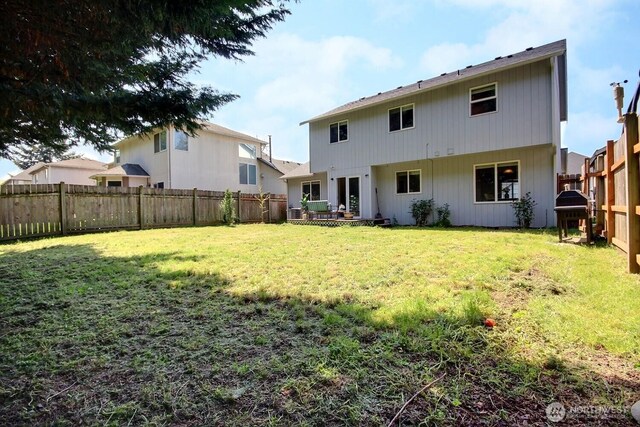 rear view of property with a fenced backyard and a yard