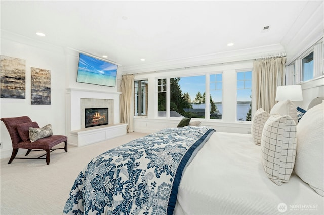 bedroom with ornamental molding, carpet flooring, a glass covered fireplace, and multiple windows