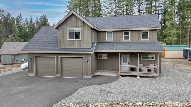 view of front facade featuring covered porch, driveway, a shingled roof, and board and batten siding