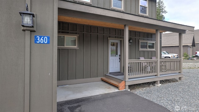 property entrance with board and batten siding and covered porch