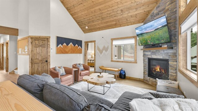 living area with a stone fireplace, wood finished floors, wooden ceiling, high vaulted ceiling, and baseboards