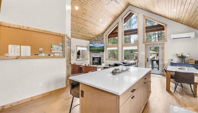 kitchen featuring a stone fireplace, a center island, light wood-type flooring, wooden ceiling, and high vaulted ceiling