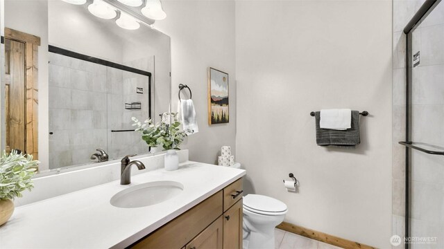 bathroom with vanity, tile patterned flooring, toilet, and tiled shower