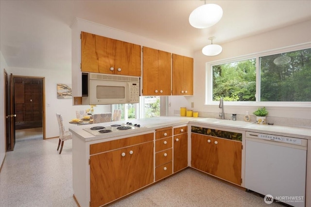 kitchen with white appliances, a sink, light countertops, and brown cabinetry