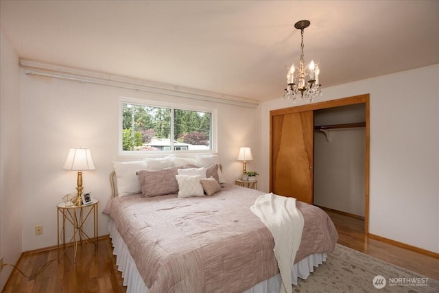 bedroom featuring a chandelier, a closet, wood finished floors, and baseboards