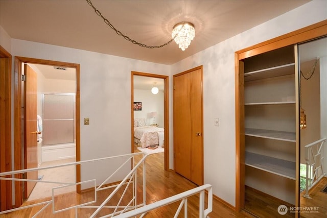 hallway with wood finished floors, a chandelier, and baseboards