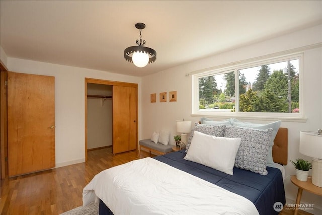 bedroom featuring a closet, wood finished floors, and baseboards