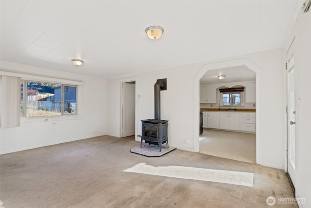 406 S Chestnut St, Ellensburg, WA 98926 - unfurnished living room with arched walkways, a wood stove, and light carpet