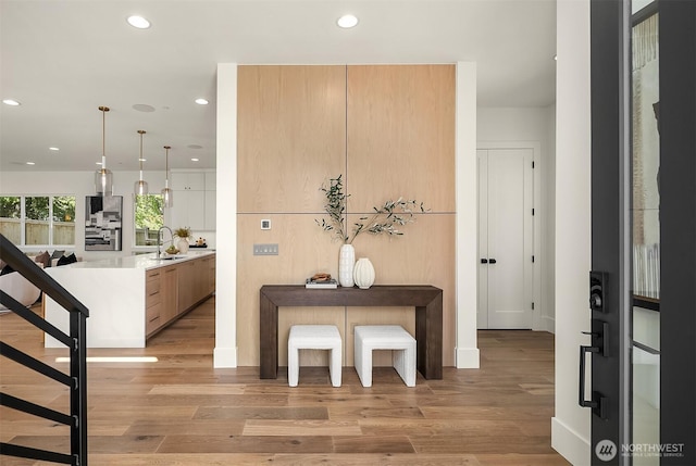 foyer with recessed lighting, light wood-type flooring, stairs, and baseboards