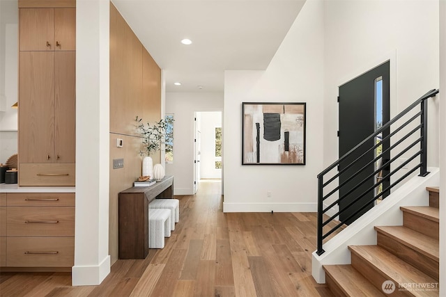 hallway with stairs, baseboards, light wood-style floors, and recessed lighting