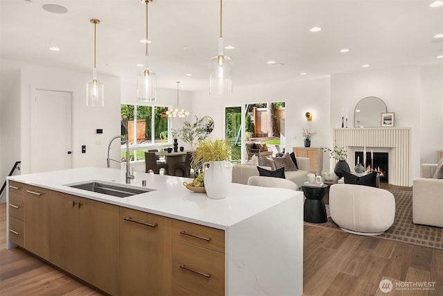 kitchen with a sink, open floor plan, light wood finished floors, light countertops, and recessed lighting