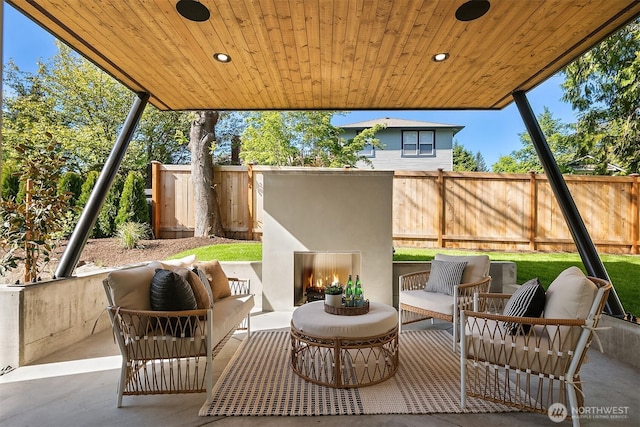view of patio with fence and an outdoor living space with a fireplace