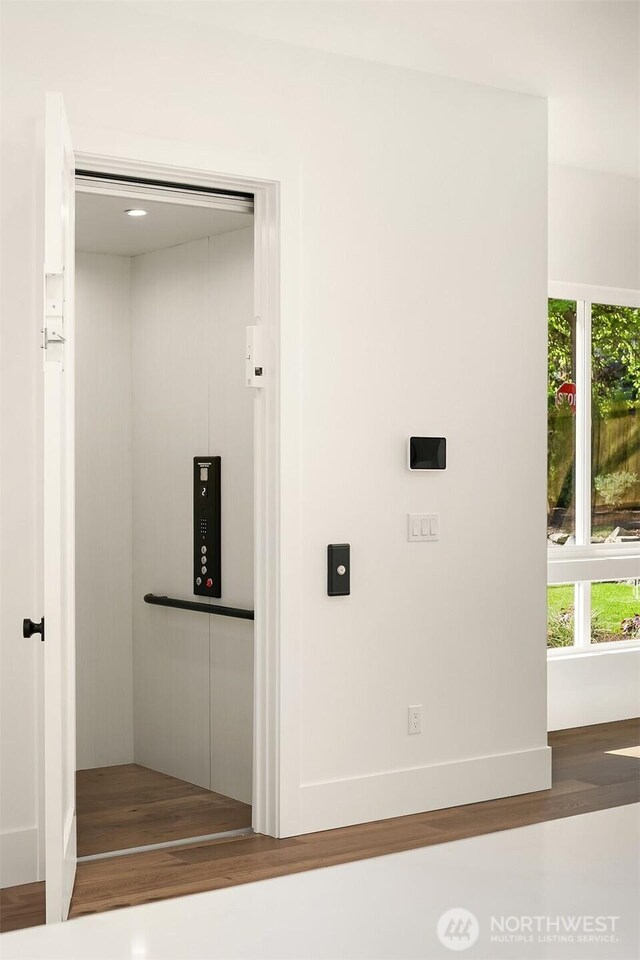 detailed view of wood finished floors, elevator, and baseboards