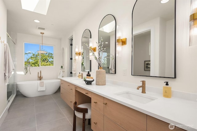 full bathroom with tile patterned floors, a skylight, double vanity, a freestanding tub, and a stall shower
