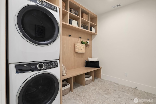 laundry area with stacked washer / drying machine and baseboards