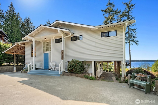 view of front of home featuring a porch, a carport, driveway, and a water view