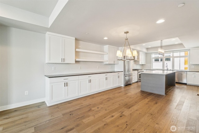 kitchen with appliances with stainless steel finishes, a raised ceiling, a chandelier, recessed lighting, and tasteful backsplash