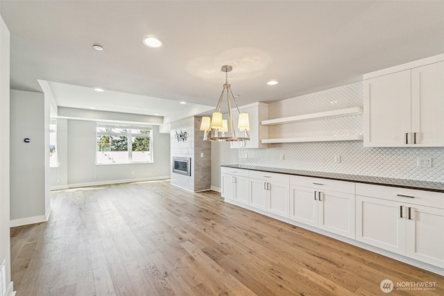 kitchen with decorative backsplash, a fireplace, open shelves, white cabinets, and open floor plan