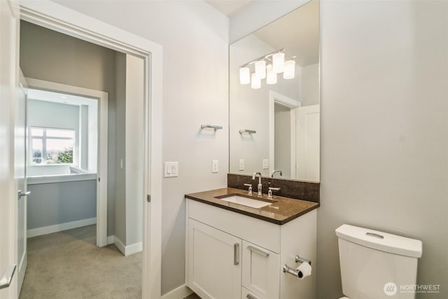 half bath featuring vanity, baseboards, and toilet
