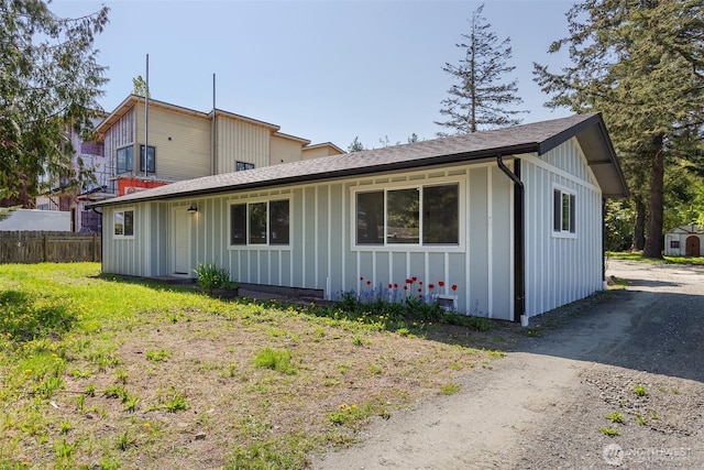 exterior space featuring fence, board and batten siding, and a shingled roof