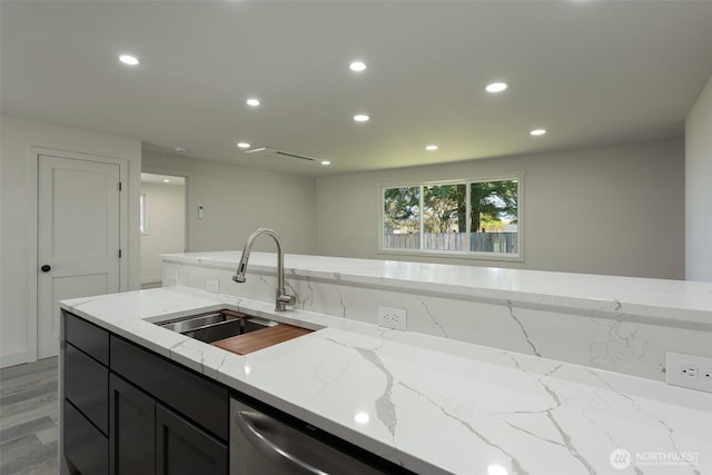 kitchen with recessed lighting, a sink, light wood-style flooring, and light stone countertops