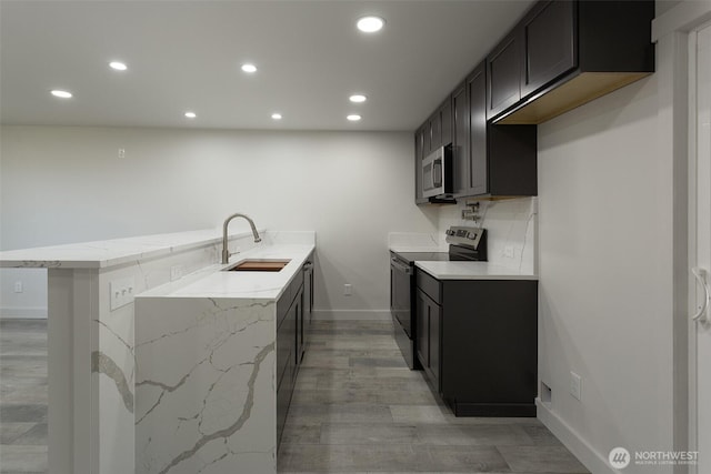 kitchen with a sink, appliances with stainless steel finishes, baseboards, and recessed lighting