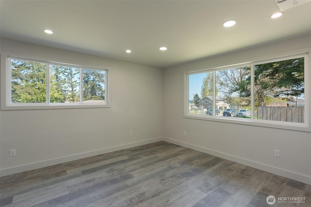 spare room with baseboards, recessed lighting, and wood finished floors