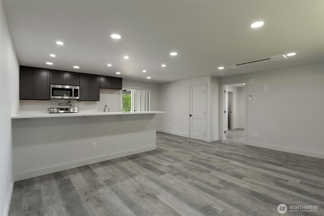 kitchen featuring light wood-style floors, light countertops, stainless steel microwave, and recessed lighting