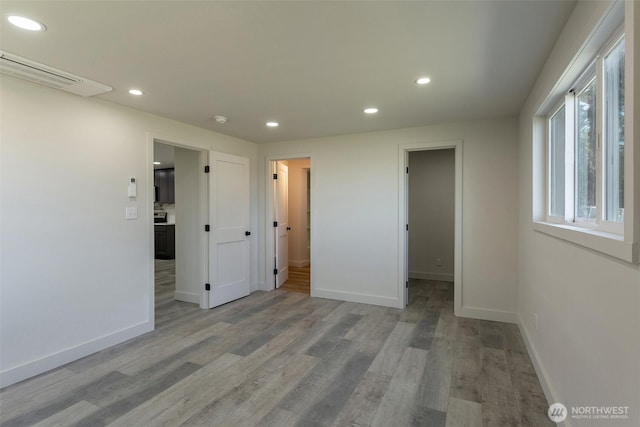 empty room with baseboards, recessed lighting, and wood finished floors