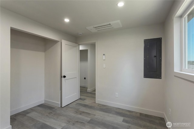 unfurnished bedroom with recessed lighting, baseboards, wood finished floors, and electric panel