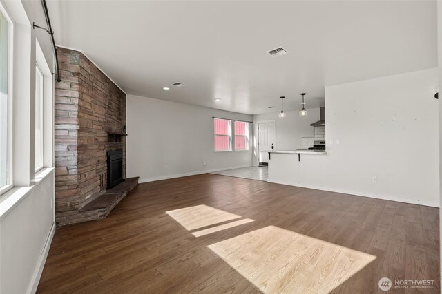 801 E Manitoba Ave, Ellensburg, WA 98926 - unfurnished living room with a stone fireplace, visible vents, baseboards, and wood finished floors