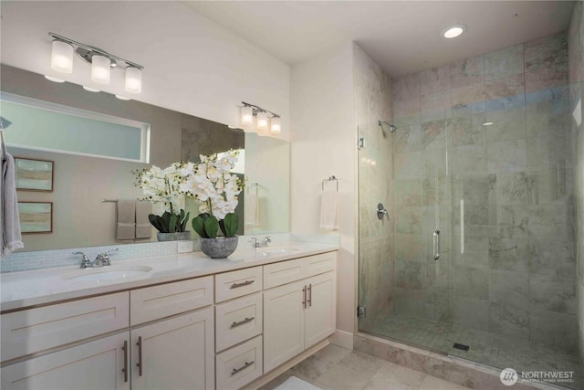 full bath featuring double vanity, a sink, a stall shower, and recessed lighting