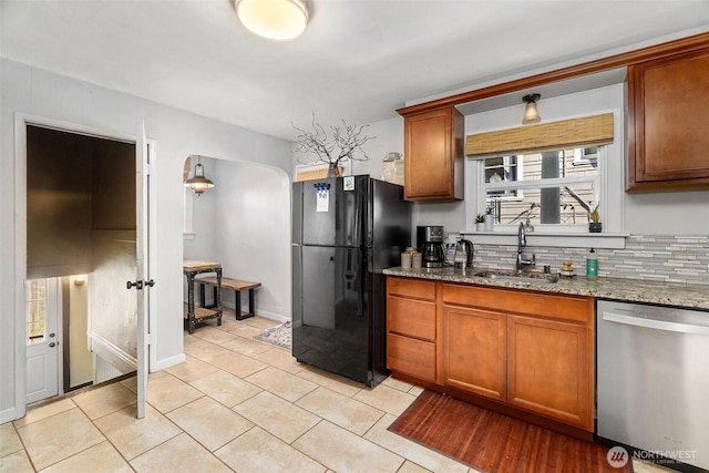 707 N 10th St, Tacoma, WA 98403 - kitchen with stainless steel dishwasher, a sink, brown cabinetry, stone countertops, and freestanding refrigerator