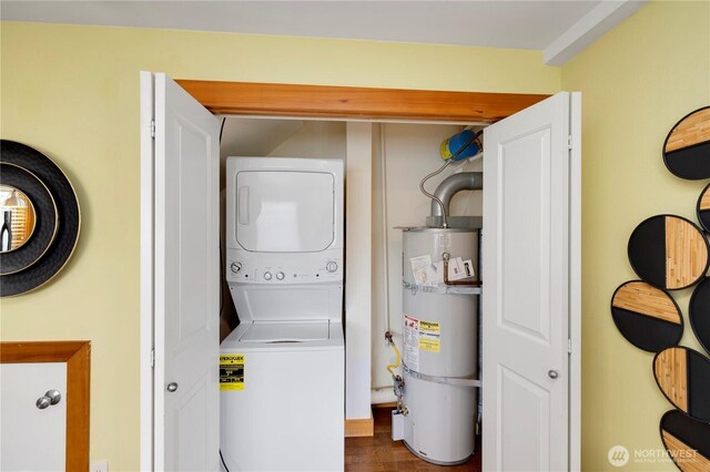 washroom with secured water heater, stacked washer / drying machine, dark wood finished floors, and laundry area