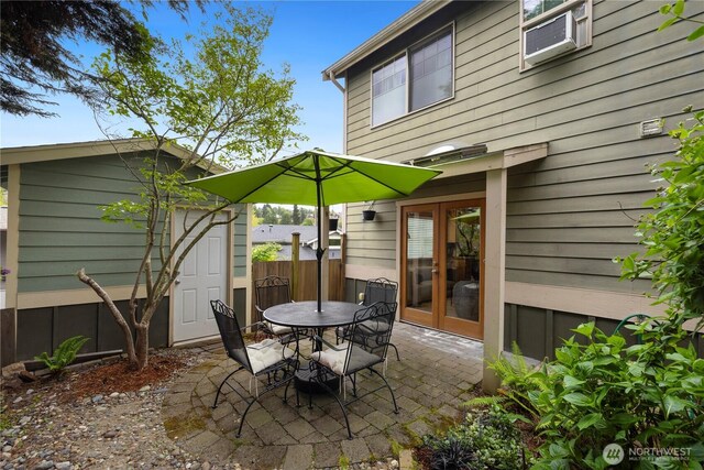 view of patio with fence, an outdoor structure, outdoor dining space, and french doors