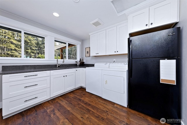 kitchen with washing machine and clothes dryer, a sink, white cabinetry, dark wood-style floors, and freestanding refrigerator
