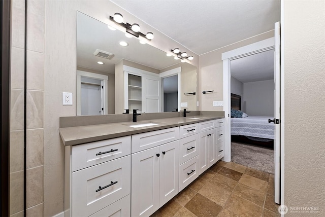 bathroom with ensuite bathroom, visible vents, a sink, and double vanity