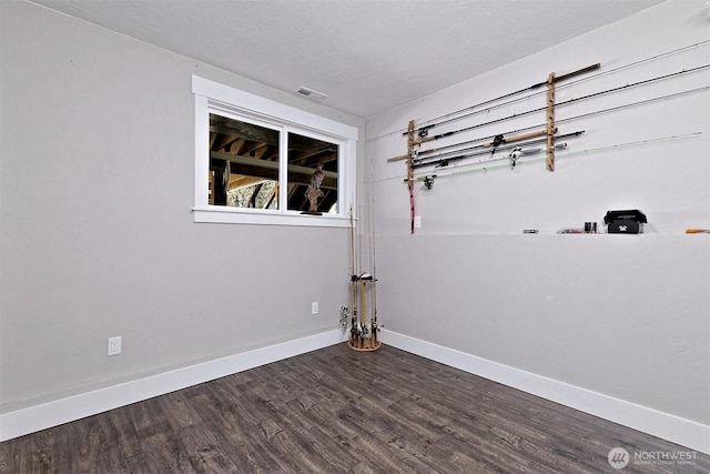unfurnished room with baseboards, wood finished floors, and visible vents