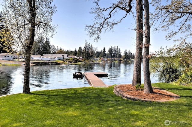 view of dock with a lawn and a water view