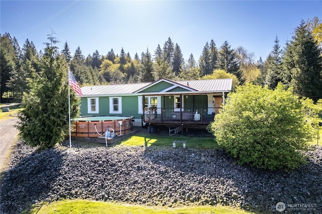 view of front of house with covered porch, a hot tub, and metal roof