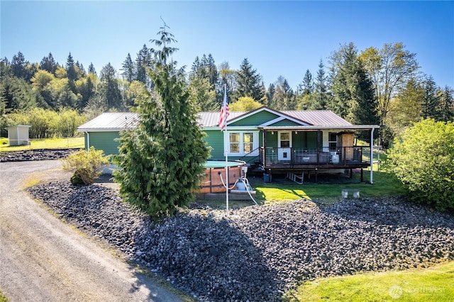 view of front of property with a porch, a front lawn, metal roof, and a jacuzzi