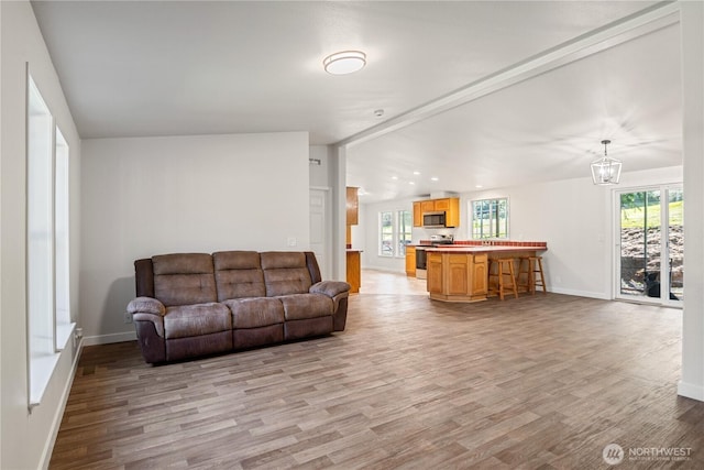 living room featuring baseboards, wood finished floors, and an inviting chandelier