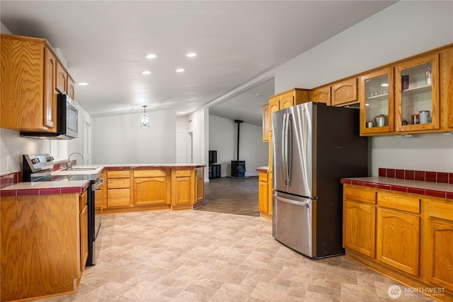 kitchen with stainless steel appliances, a peninsula, recessed lighting, glass insert cabinets, and tile countertops
