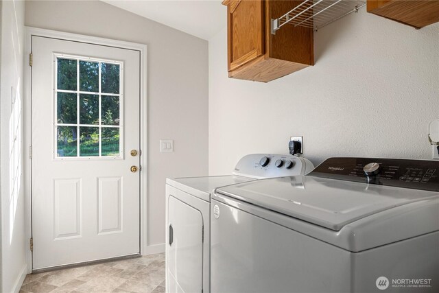 laundry area with washing machine and clothes dryer, baseboards, and cabinet space