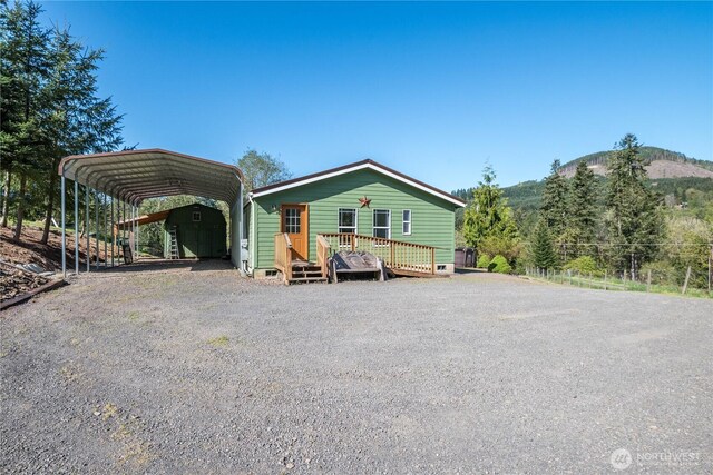 view of front facade with a carport, gravel driveway, and a deck with mountain view