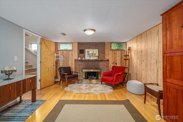5015 SW Prince St, Seattle, WA 98116 - sitting room featuring stairs, wood finished floors, wooden walls, a brick fireplace, and plenty of natural light