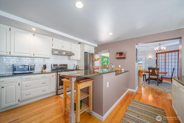 5015 SW Prince St, Seattle, WA 98116 - kitchen featuring appliances with stainless steel finishes, under cabinet range hood, white cabinetry, light wood-style floors, and recessed lighting
